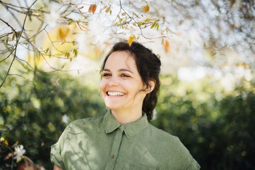 Natali Rejek, Webdesignerin von Leuchtraum Webdesign, lächelnd vor leuchtendem Hintergrund.